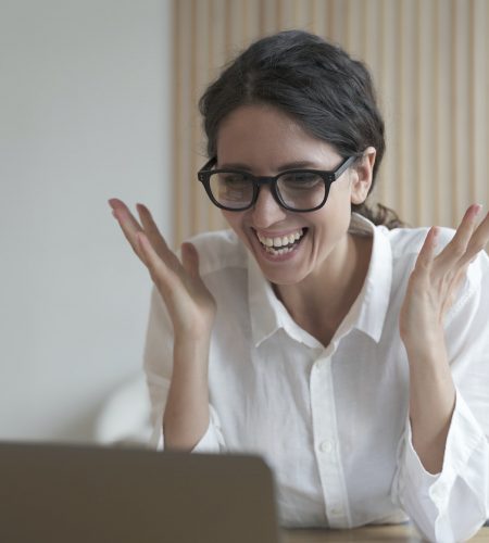 Joyful coach italian lady looks at laptop screen while communicating with students online